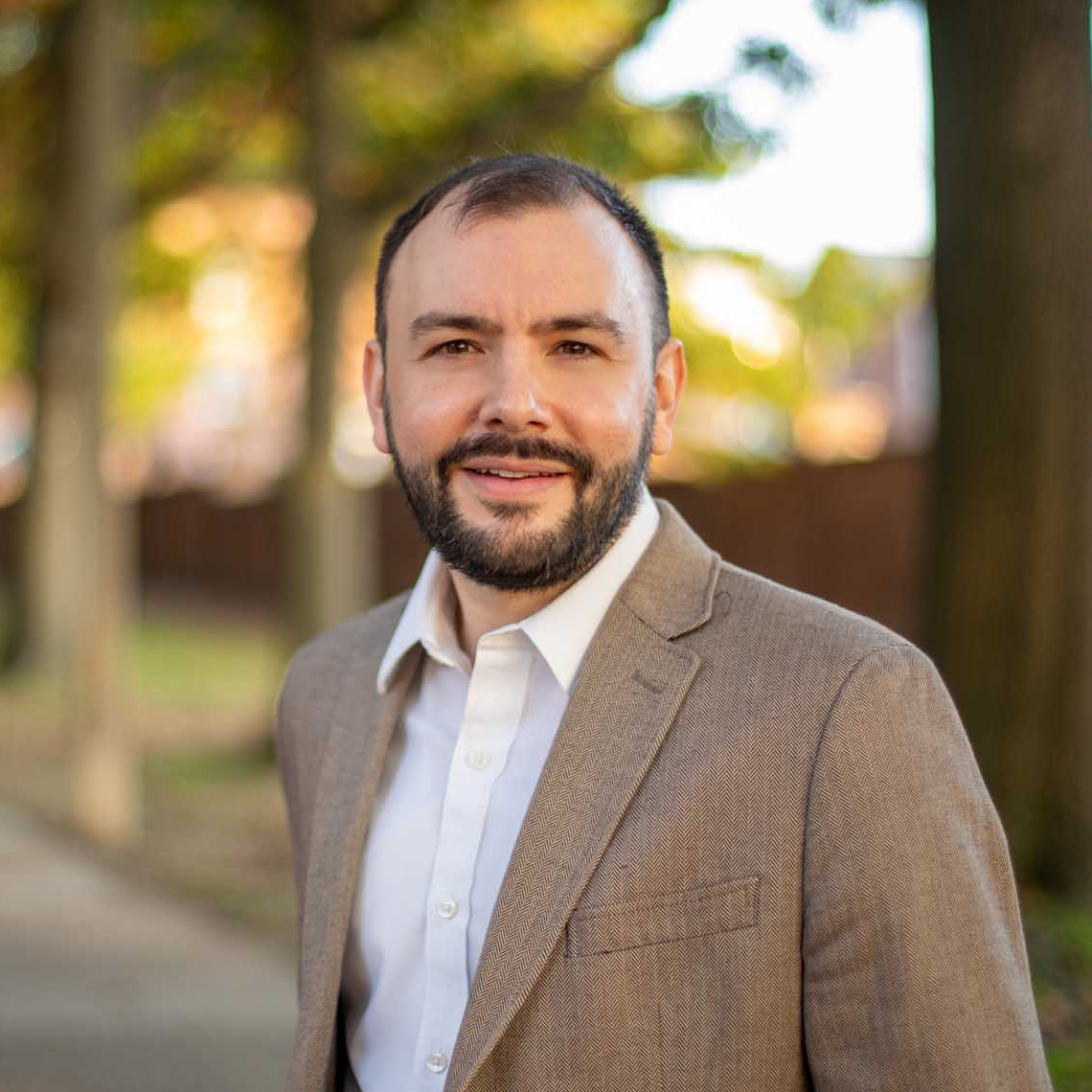 Photo of Jacob Moses outside in front of trees and a brick wall.